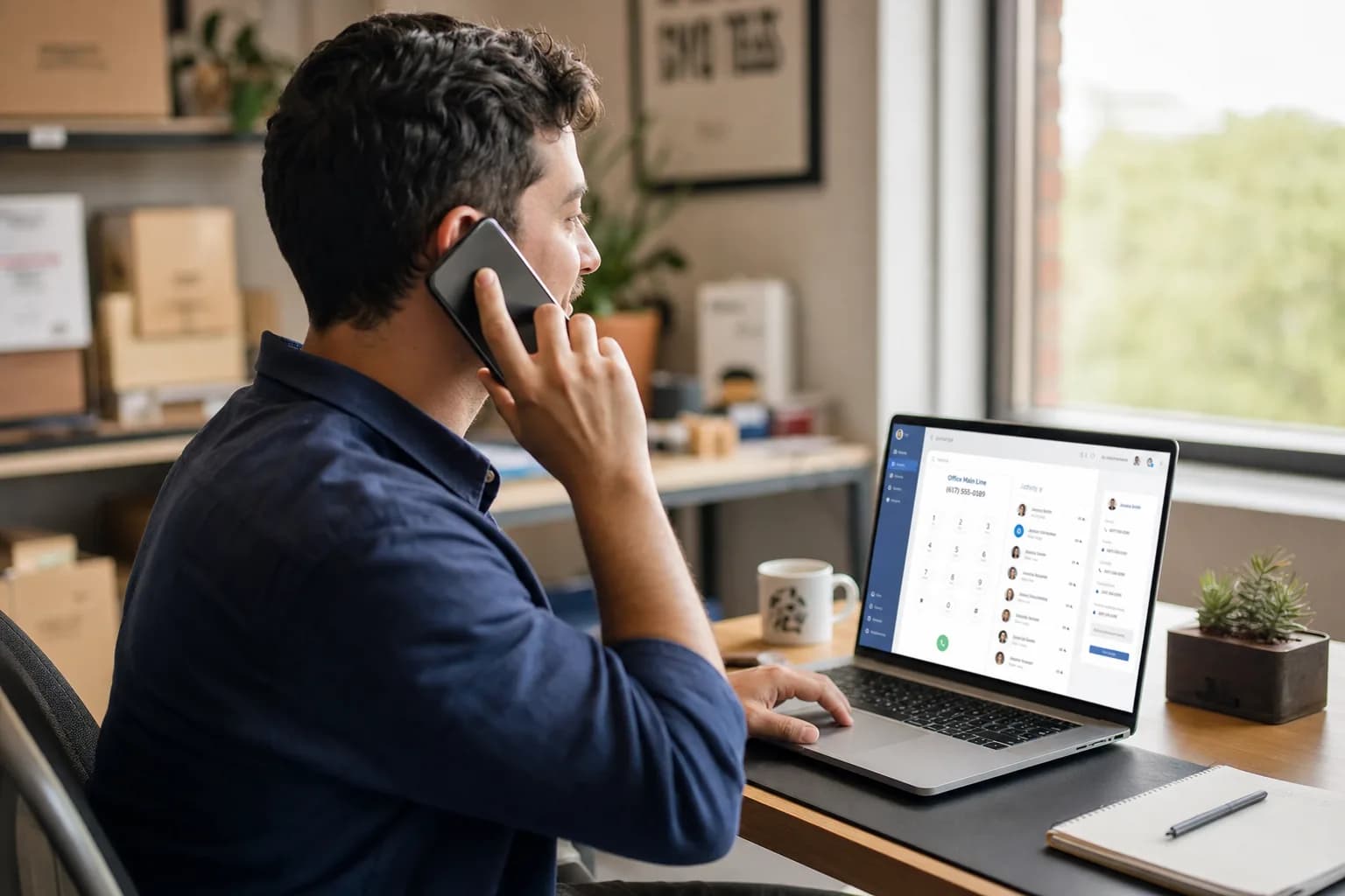 A small business owner talking on a mobile phone while checking a laptop dashboard, choosing the best voip service for small business